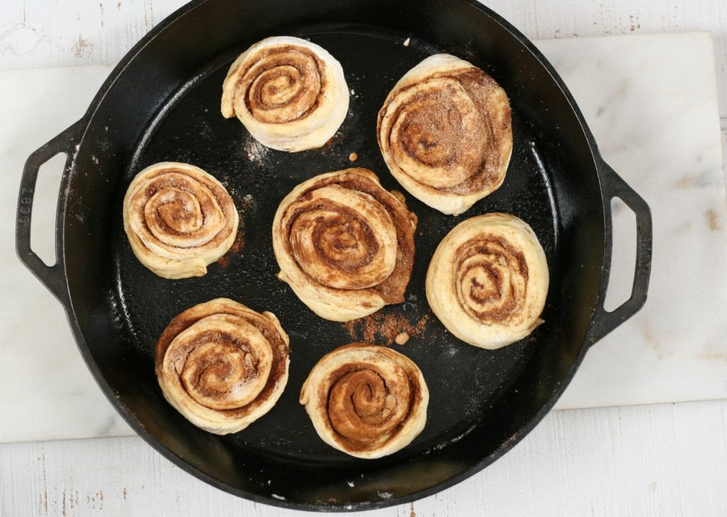 cinnamon rolls rising in a 17-inch cast iron two-handle pan