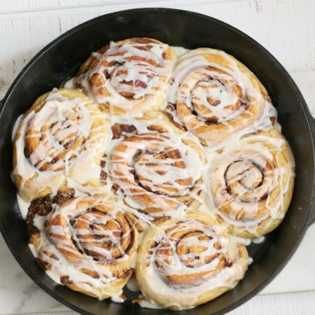 cinnamon rolls in a cast iron pan drizzled with icing