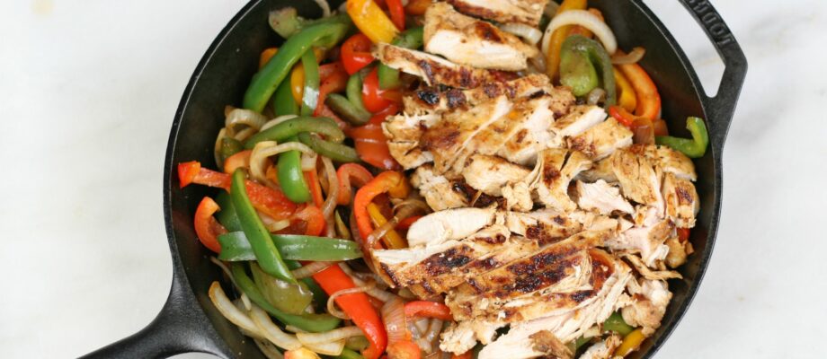 grilled chicken and sauteed onions and multi colored bell peppers in a cast iron skillet