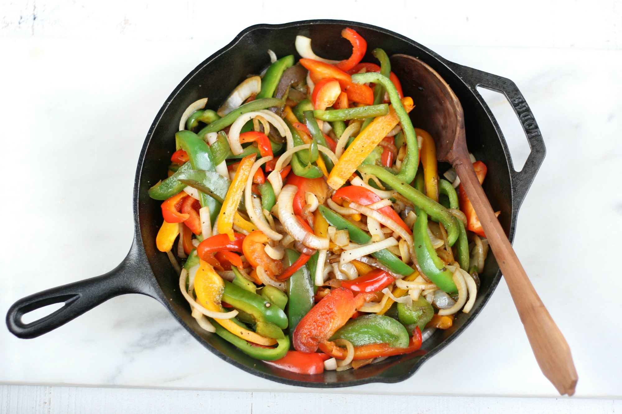 sauteed onions and peppers in a cast iron skillet and hand carved wooden spoon.