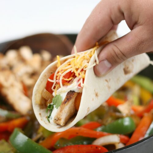 Chicken fajitas with onions and peppers being hand held