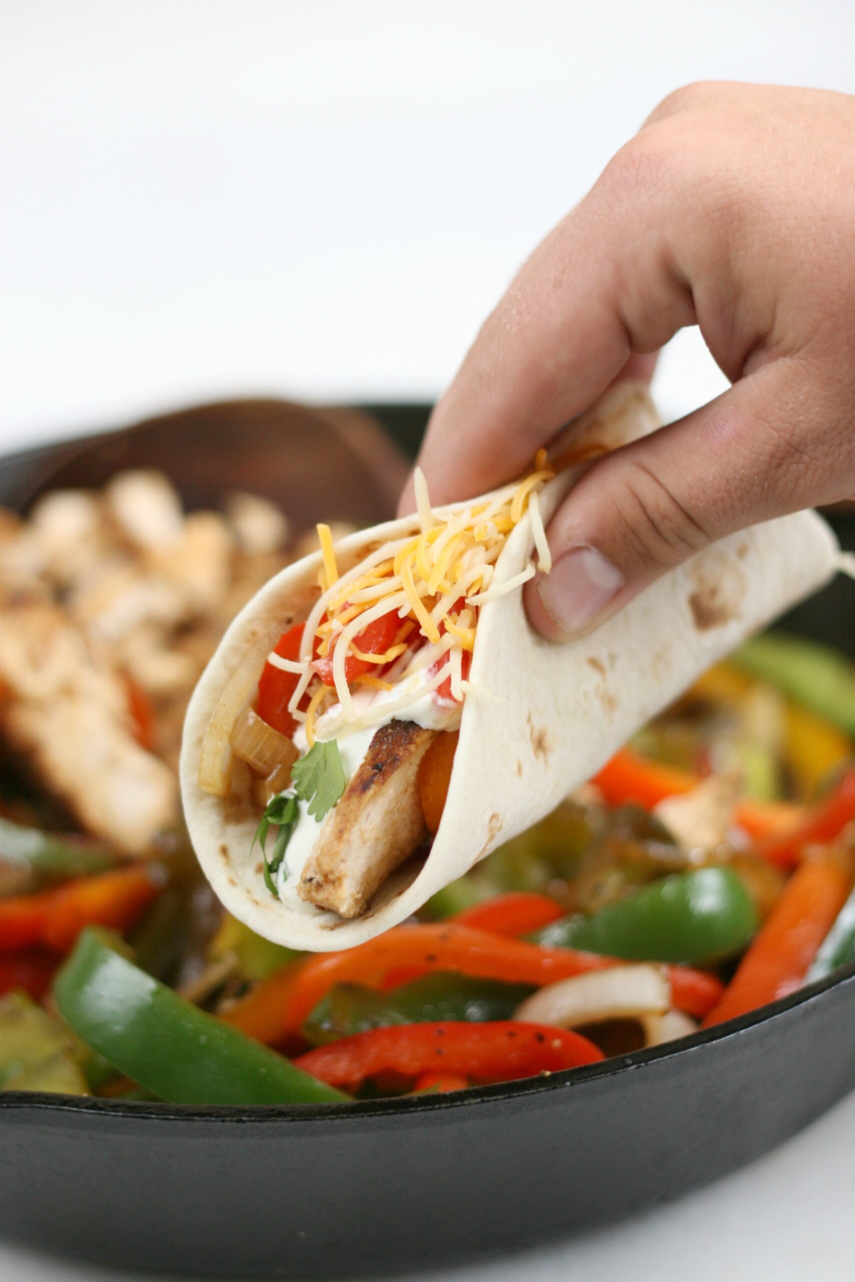 Chicken fajitas with onions and peppers being hand held.