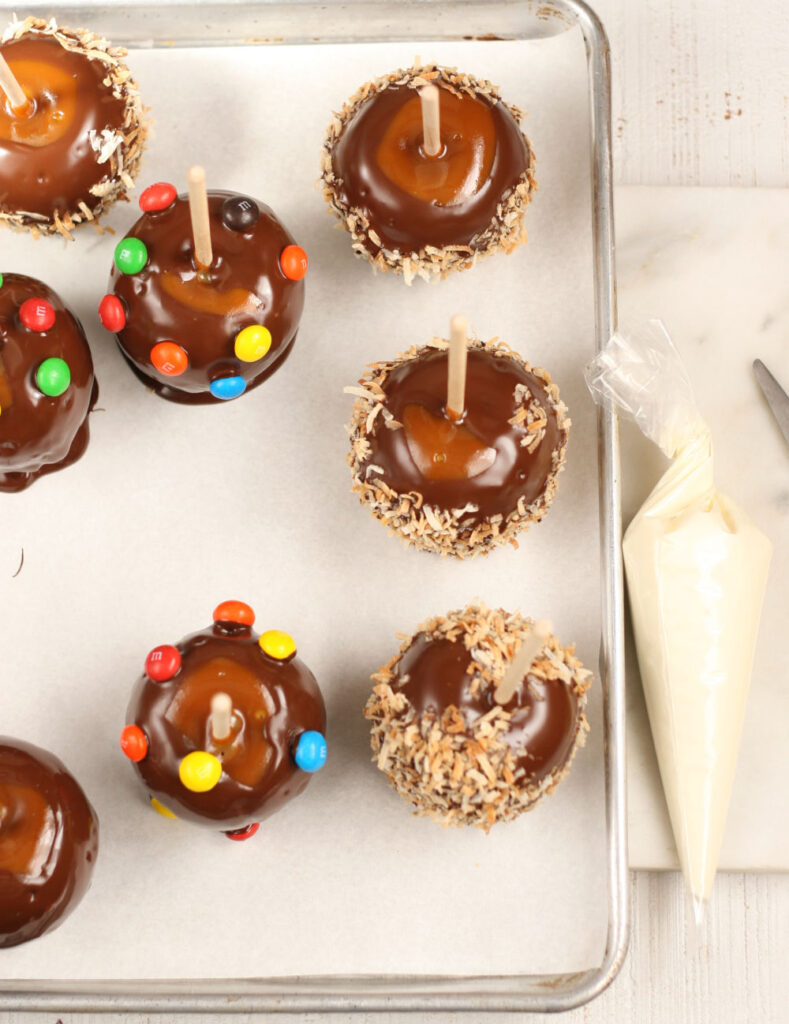 Caramel and chocolate dipped apples on a half sheet pan