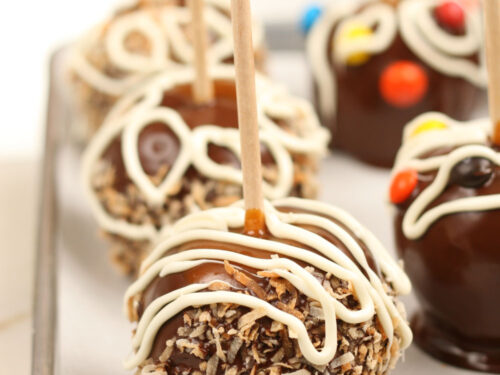 caramel chocolate apples rolled in toasted coconut on sheet pan