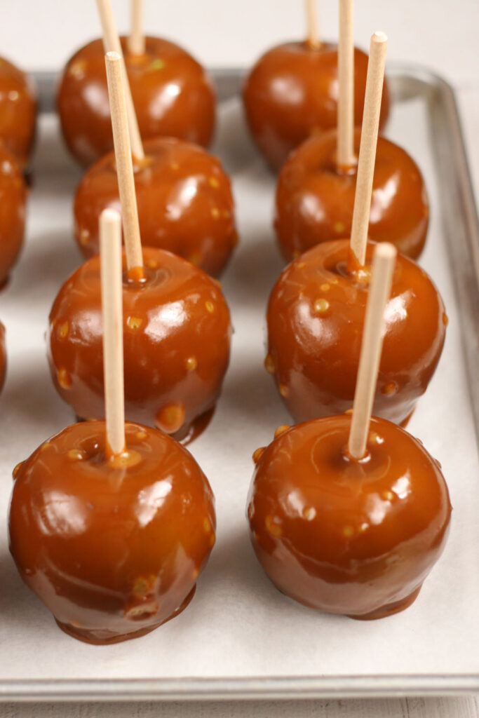 caramel dipped Granny Smith apples on a half sheet pan