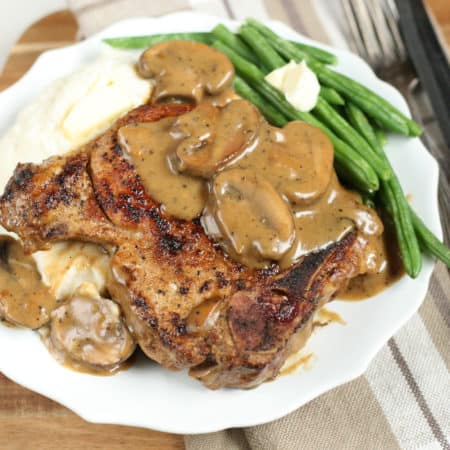 cast iron pork chops with a mushroom cream sauce and mashed potatoes on a white plate