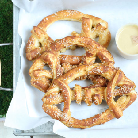 Football shaped soft pretzels with sea salt sitting in a galvanized tray