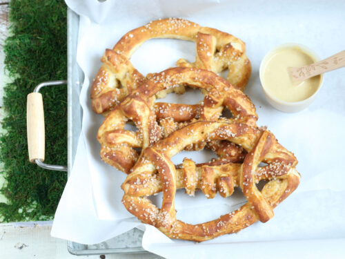 Football shaped soft pretzels with sea salt sitting in a galvanized tray