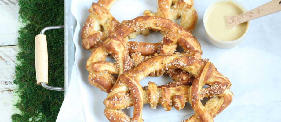Football shaped soft pretzels with sea salt sitting in a galvanized tray
