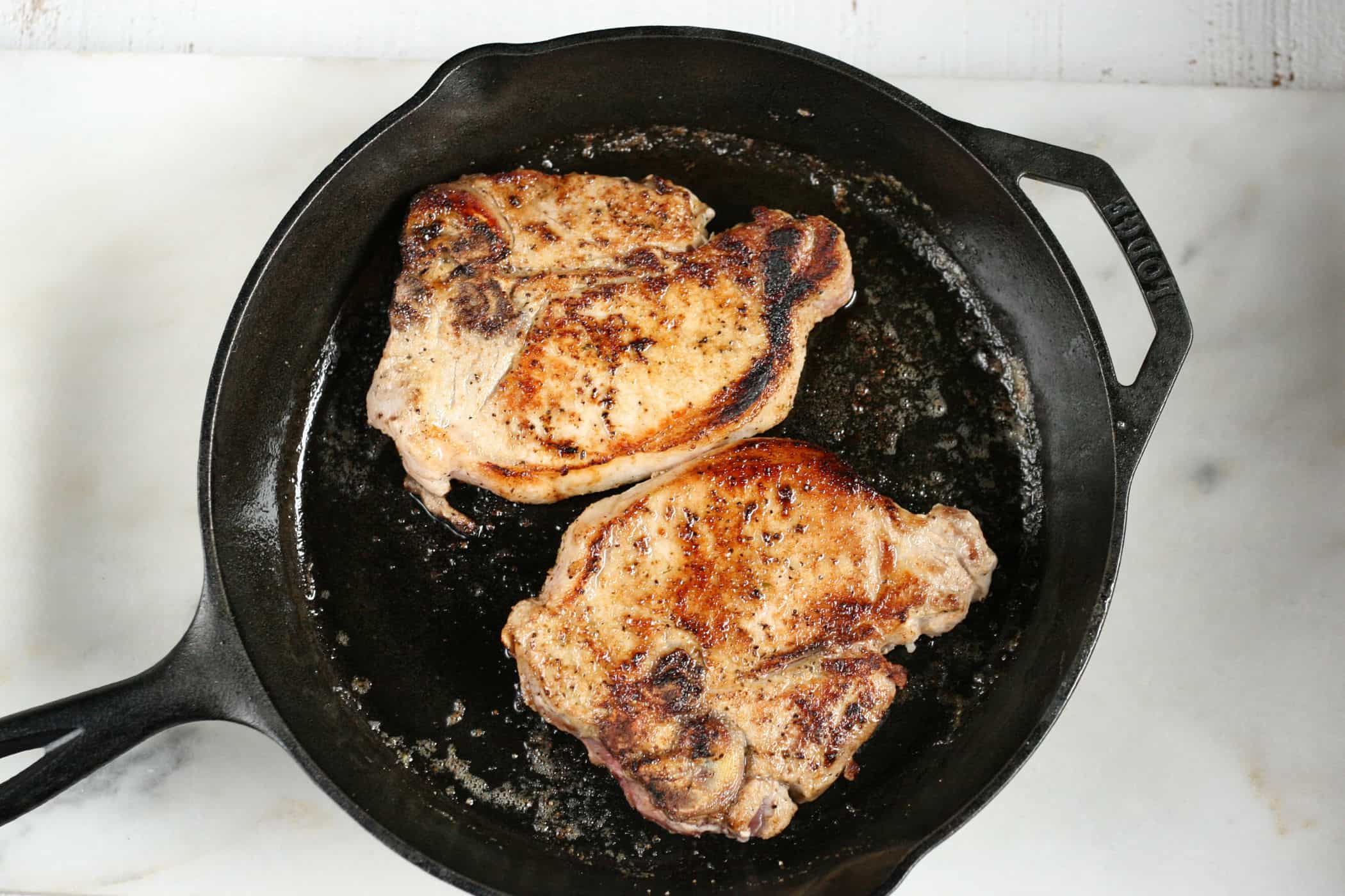 browning pork chops in a cast iron skillet