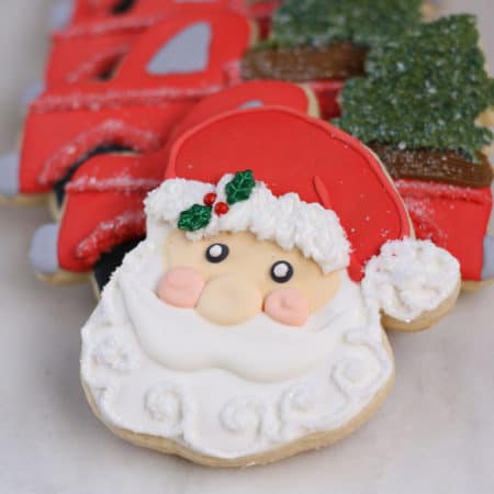 Santa face decorated sugar cookie with holly in his hat