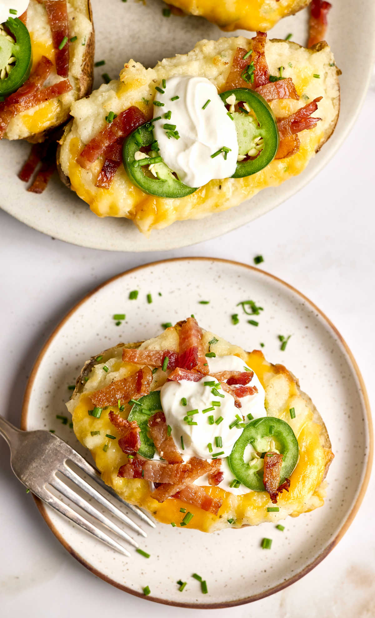 Twice baked potatoes on small white speckled plate.