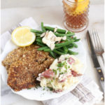 Almond crusted Tilapia filets on a plate with fresh green beans and smashed red potatoes