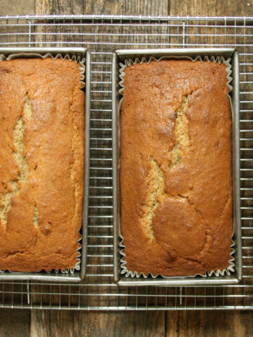Three loaves of banana bread in metal baking pans cooling.