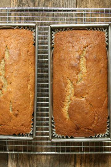 Three loaves of banana bread in metal baking pans cooling.