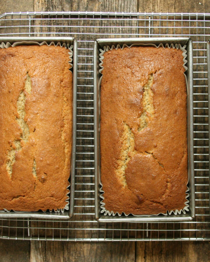 Three loaves of banana bread in metal baking pans cooling.