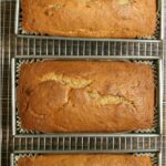 banana bread in metal loaf pans cooling on baking rack, on reclaimed barn boards