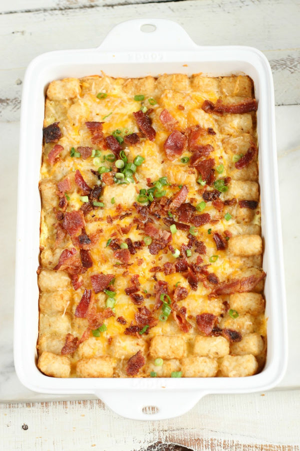 tater tots and bacon on top of a breakfast casserole in white casserole dish