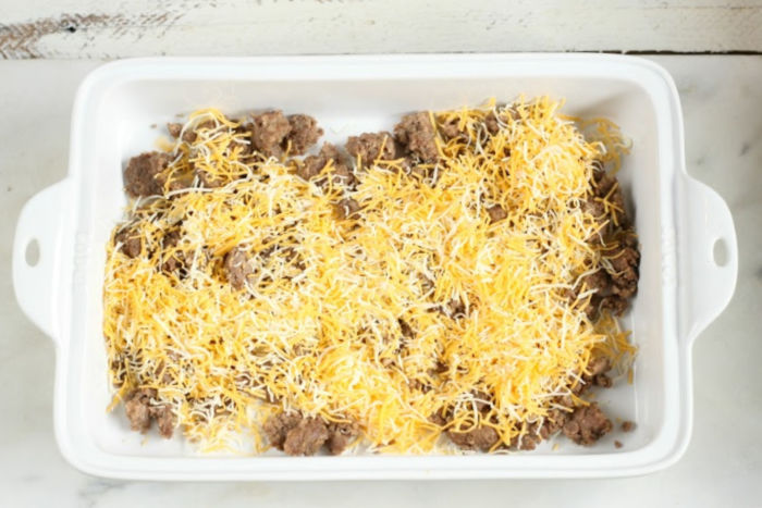 rectangle white ceramic baking dish with cooked sausage and shredded cheese