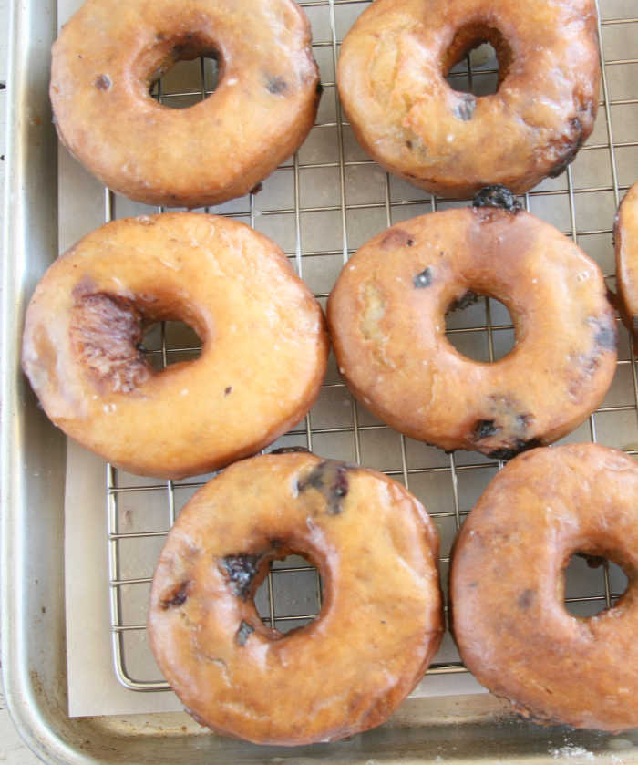 blueberry doughnuts with glaze drying on baking rack