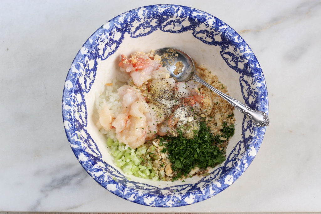 cooked lobster in blue speckled edge bowl with bread crumbs and seasonings