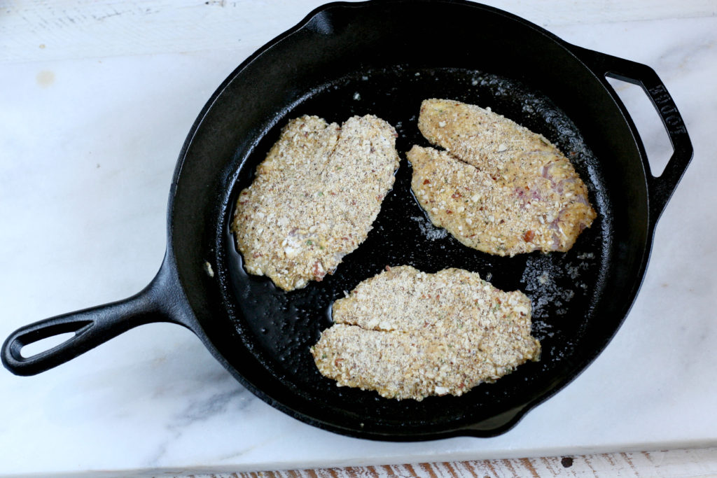 Almond crusted Tilapia filets being cooked in a cast iron skillet