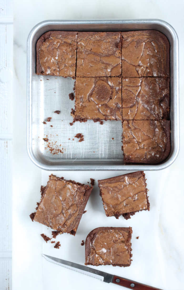 square metal baking pan with homemade brownies cut into squares.