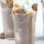 Clear glass ice cream cups with frozen hot chocolate, cookie pieces, caramel sauce, and whipped cream.