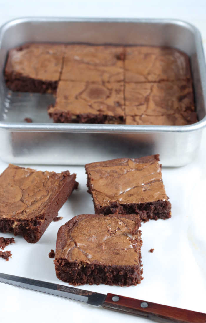 squares of homemade brownies cut up in front of square metal baking dish.