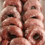 Red Velvet doughnuts lined up against each other in a galvanized metal serving tray