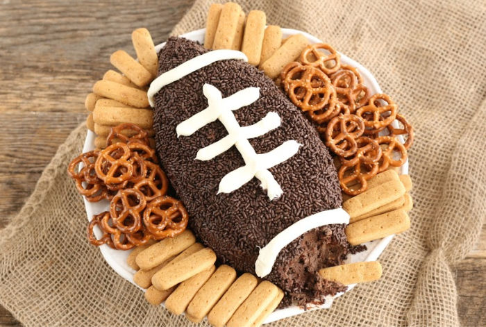 football shaped brownie batter dip. covered in chocolate sprinkles, surrounded by pretzels and graham cracker sticks