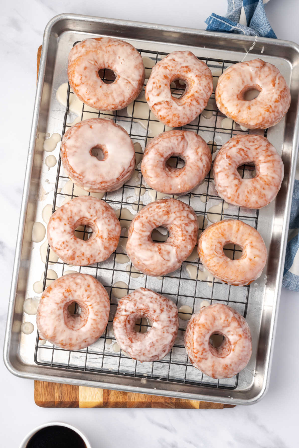 Glazed donuts drying on baking rack.