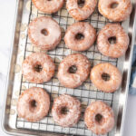 Glazed donuts drying on baking rack.
