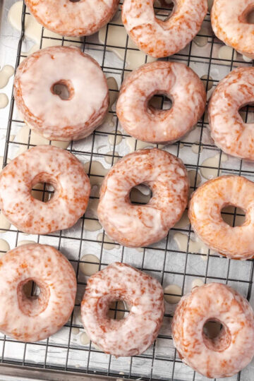 Glazed donuts drying on baking rack.