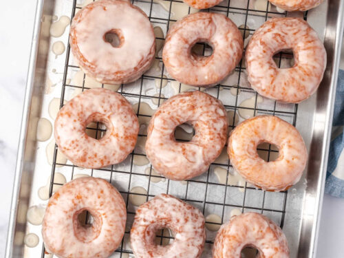 Glazed donuts drying on baking rack.