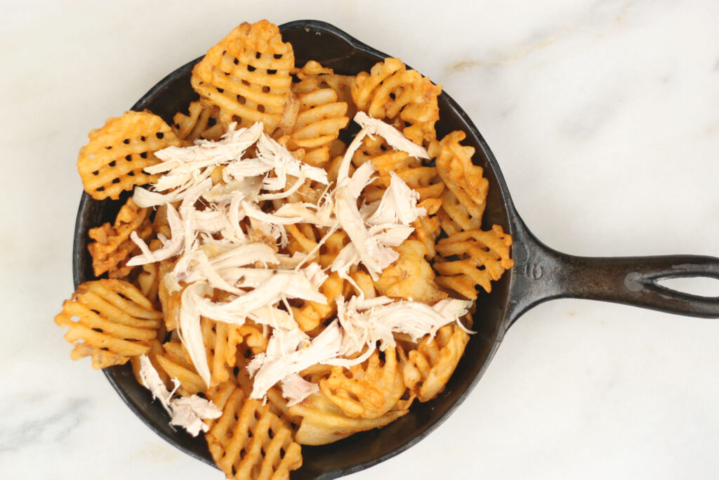 pulled chicken on top of waffle fries in small cast iron skillet