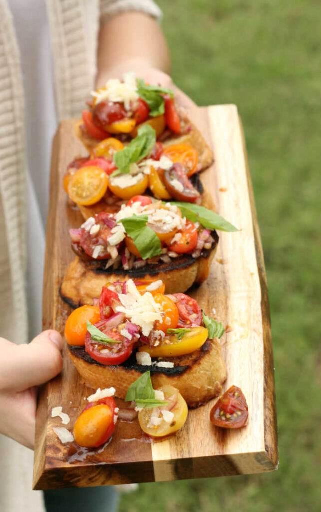 tomato bruschetta with heirloom cherry tomatoes, fresh basil, shaved Parmesan cheese, on wooden cutting board