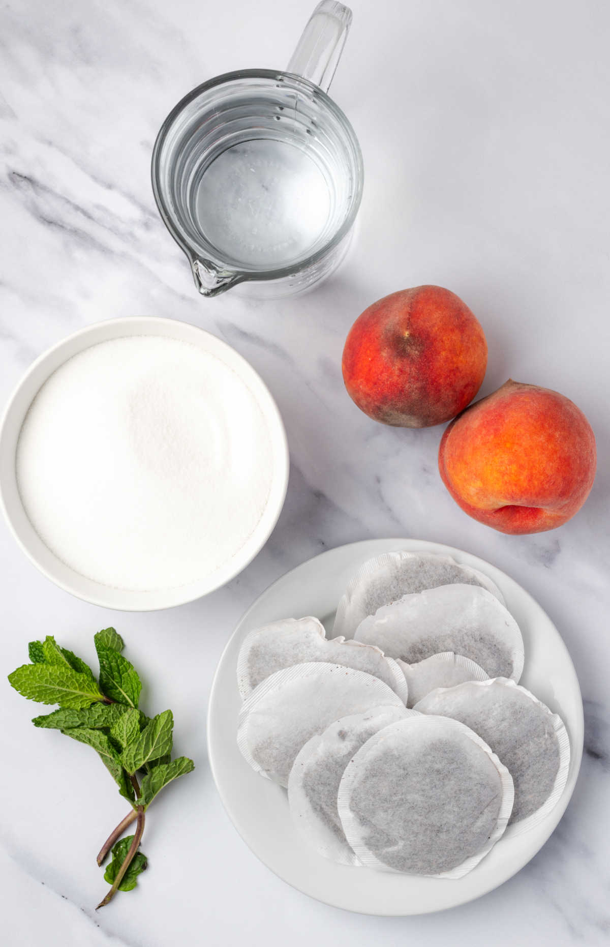Ingredients for iced tea in small white bowls, fresh peaches.