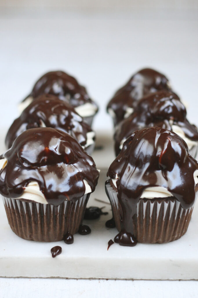 Covering chocolate cupcakes with peanut butter frosting with melted chocolate ganache