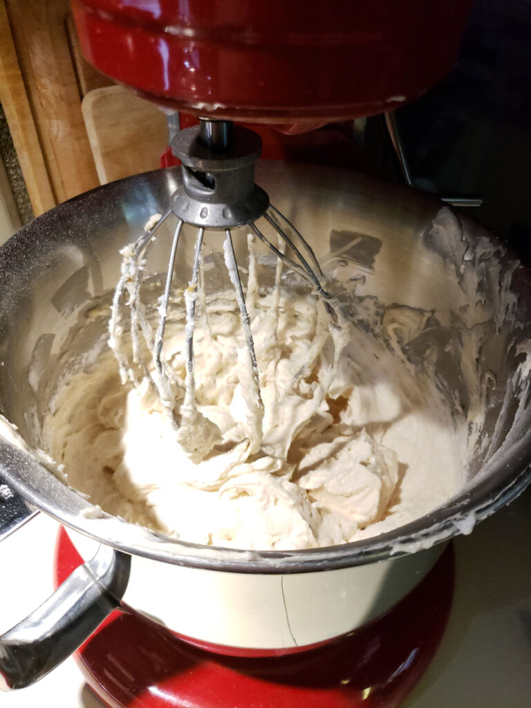 close up of beater in Red KitchenAid mixer with peanut butter frosting