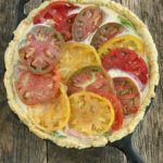 Quiche with heirloom tomato slices in cast iron skillet.