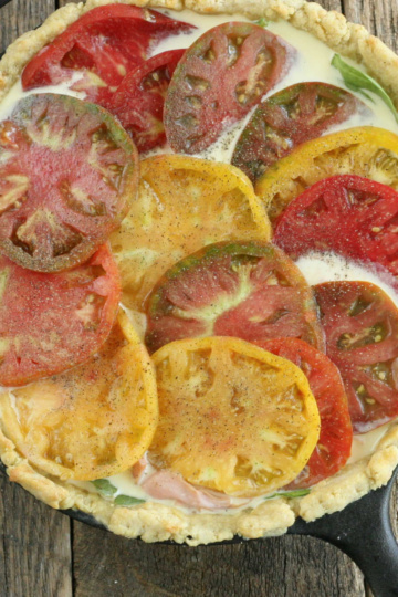 Quiche with heirloom tomato slices in cast iron skillet.