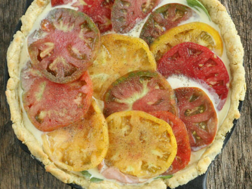 Quiche with heirloom tomato slices in cast iron skillet.