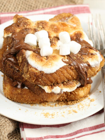 S'more French toast stacked on plate with toasted marshmallows and drizzled with Nutella Hazelnut spread