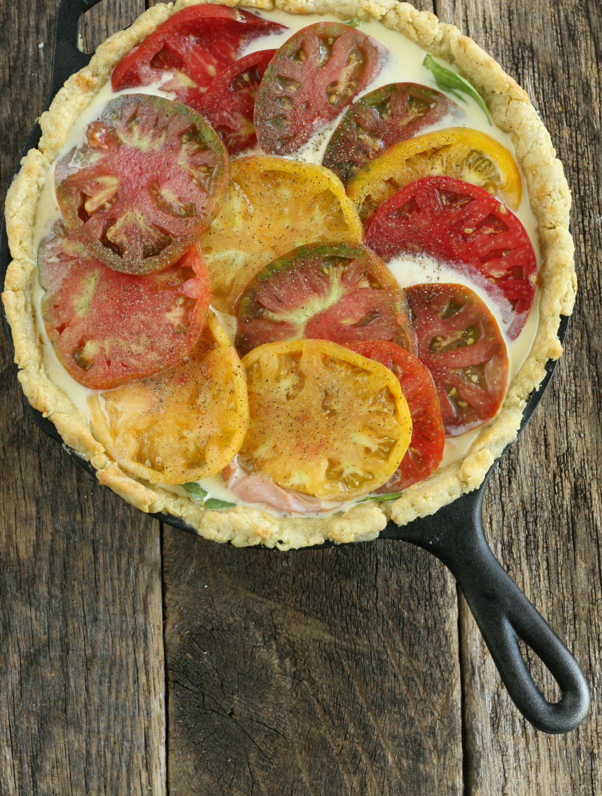 quiche with colorful heirloom tomatoes on top.