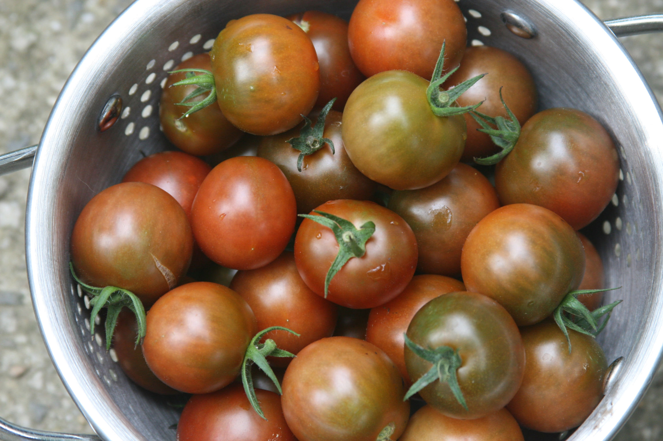 Cherry tomatoes in a metal colander.