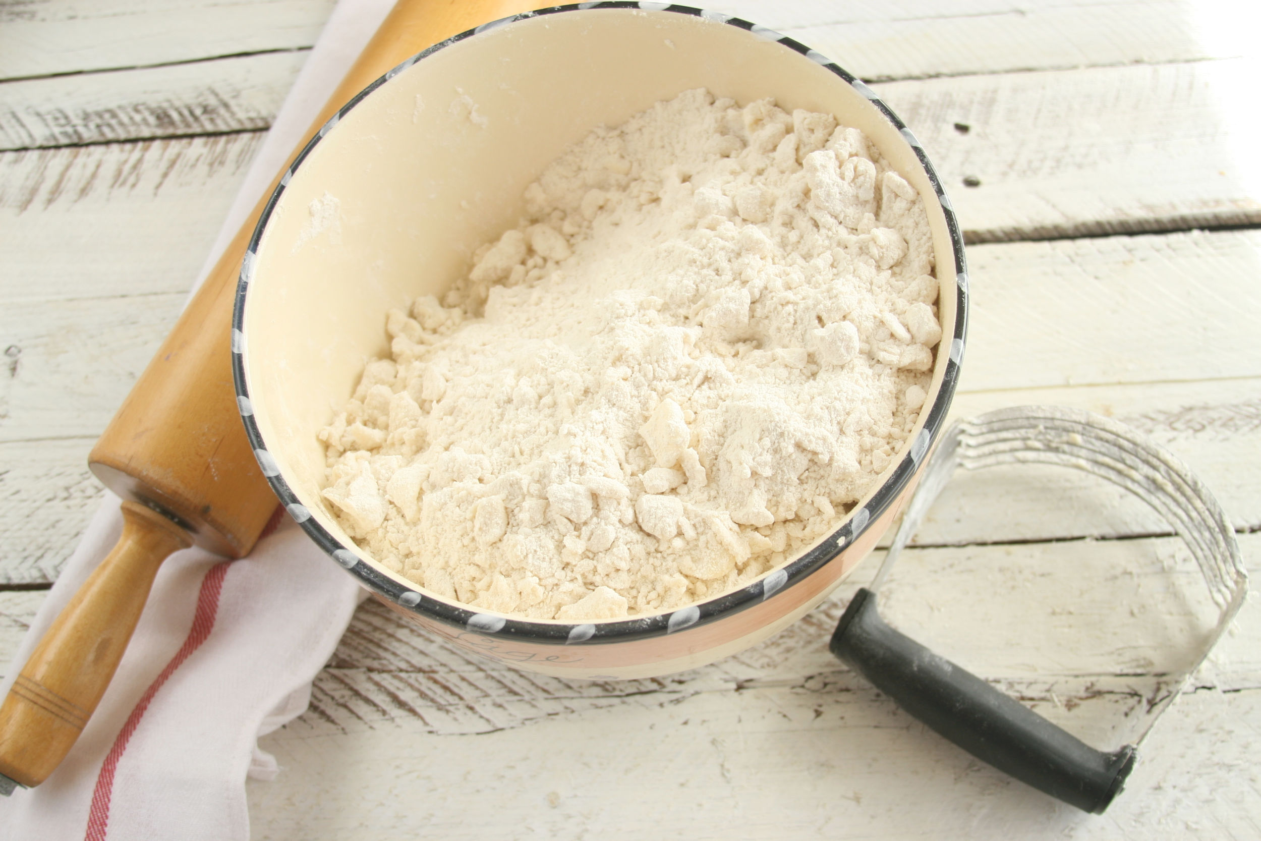 large mixing bowl with flour and pea size pieces of butter and lard making pie crust.