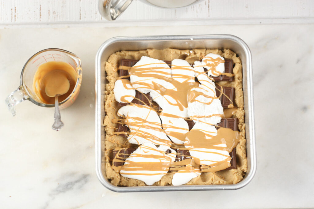 S'more bars with fluff, chocolate bars, and drizzled with melted peanut butter