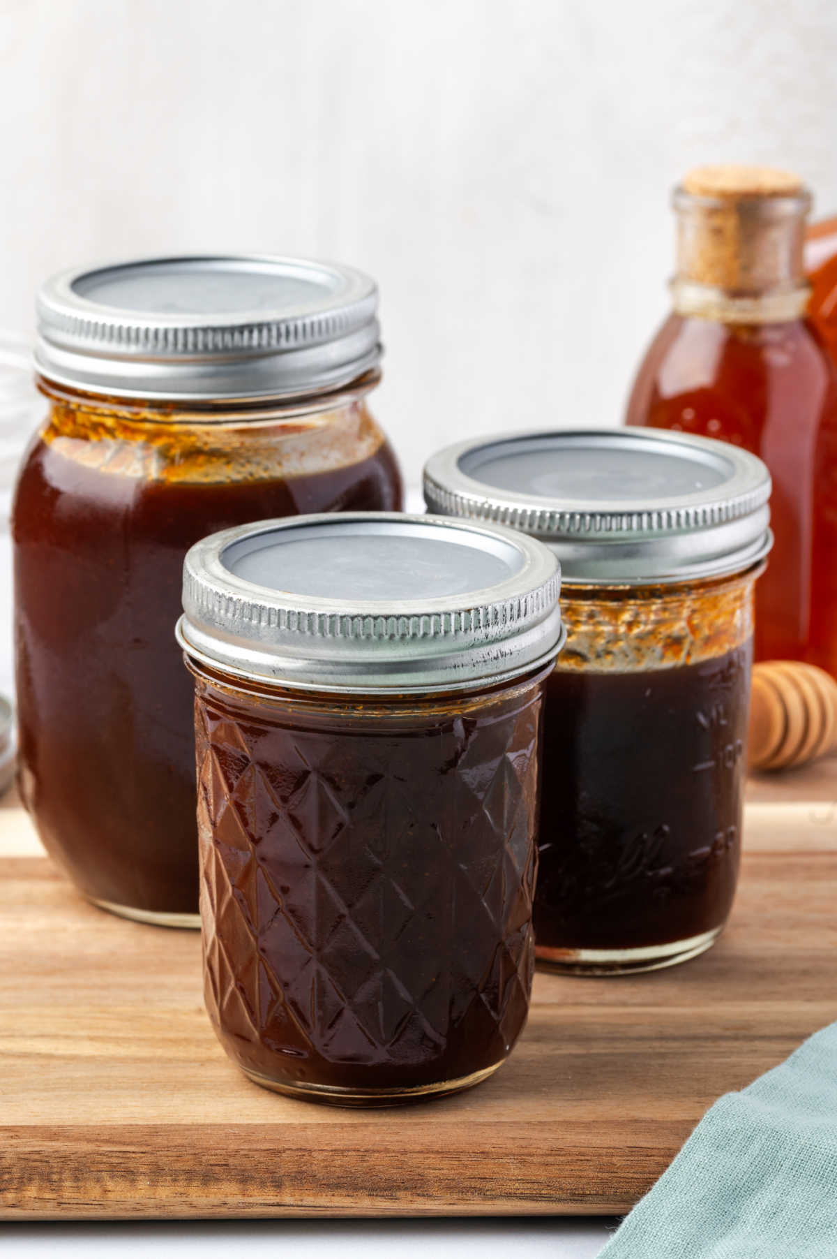 Mason jars of different sizes with barbecue sauce.