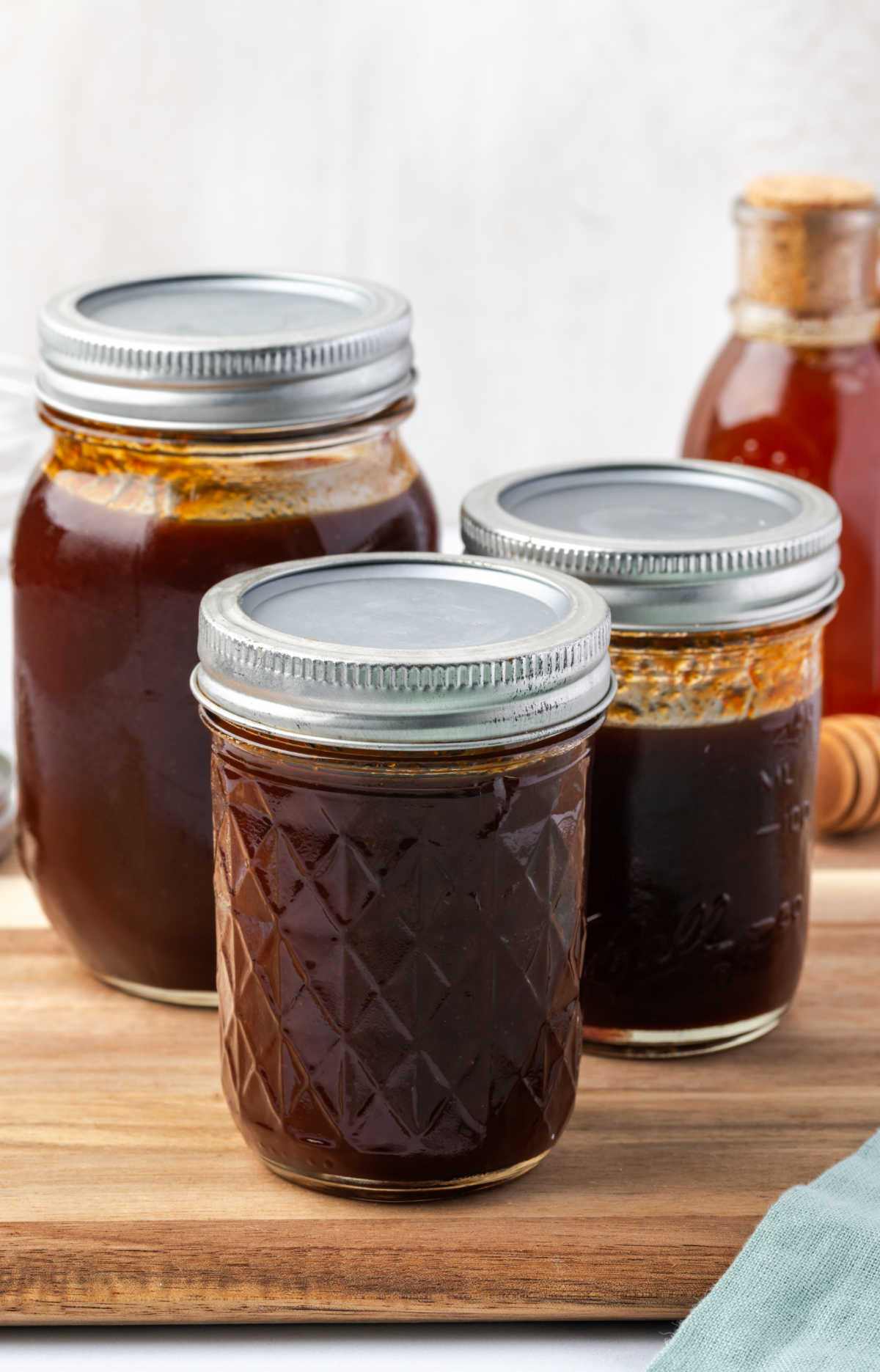Jars of barbecue sauce on cutting board.